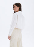 Woman wearing a white blazer and beige pants on a white background
