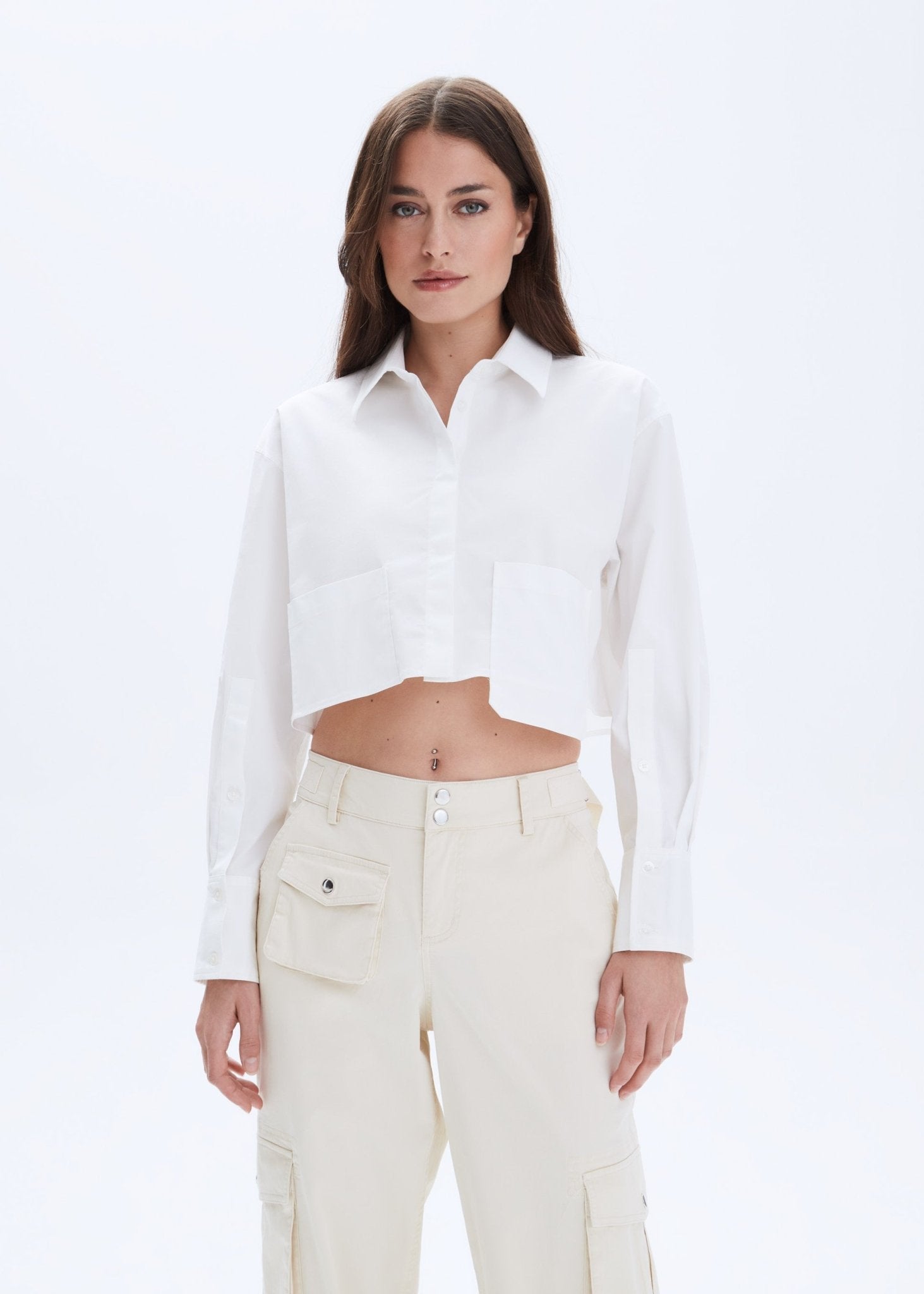 Woman wearing a white shirt and beige pants on a light gray background