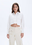 Woman wearing a white shirt and beige pants on a light gray background