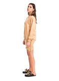 Woman wearing a beige outfit with black sandals on a white background