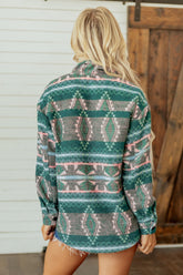 Woman viewed from behind in green, gray, and pink geometric patterned shirt