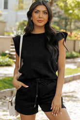 Woman wearing a black outfit with a white handbag outdoors