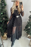 Woman in black polka dot mesh maxi dress with belt, white hat and black boots