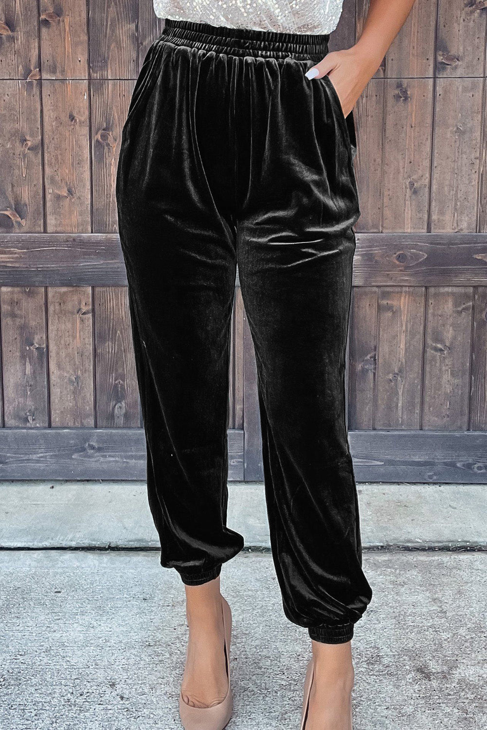 Black velvet high waist jogger pants with elastic cuffs and nude heels, front view
