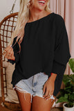 Woman wearing a black oversized top and denim shorts indoors.