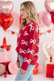 Woman in red knit sweater with white bow pattern and light blue jeans in Valentine’s room.