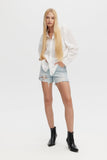 Woman wearing a white shirt, denim shorts, and black boots on a white background