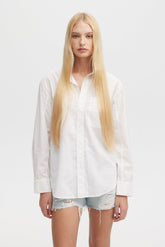 Person wearing a white shirt and denim shorts on a plain background