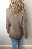 Back view of woman in brown-beige heathered cable-knit sweater and blue jeans.