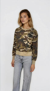 Woman wearing a camouflage sweater and jeans on a white background