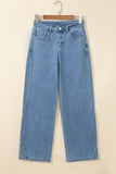 Light blue denim jeans with silver studs along the side seams on a wooden hanger.