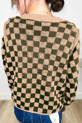 Back view of a person in an olive green and beige checkerboard knit sweater.