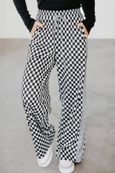 Person wearing black and white checkered pants on a plain background