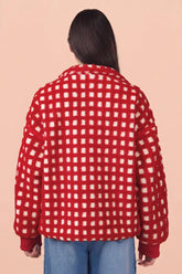 Back view of person in red and off-white checkered fuzzy cardigan with blue jeans.