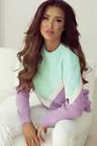 Woman wearing a colorful sweater sitting on a white couch.