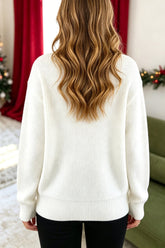 Back view of woman in cream ribbed sweater and black pants in a festive setting.