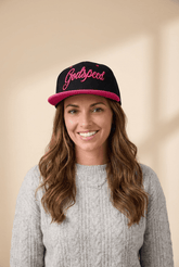 Woman wearing a black and pink cap with 'Godspeed' text on a beige background