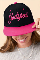 Person wearing a black and pink cap with 'Godspeed' text on a beige background