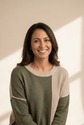 Woman wearing a green and beige sweater with a neutral background