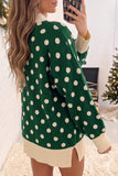 Woman in oversized green sweater with cream polka dots and ribbed trim.