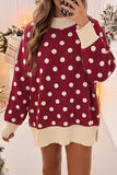 Woman in burgundy sweater with white polka dots and cream ribbed trim.