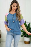 Woman wearing a colorful top with a white wall and plant in the background