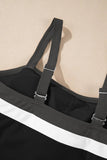 Close-up of black swimsuit with wide adjustable straps and bold white horizontal stripe across the front on beige.