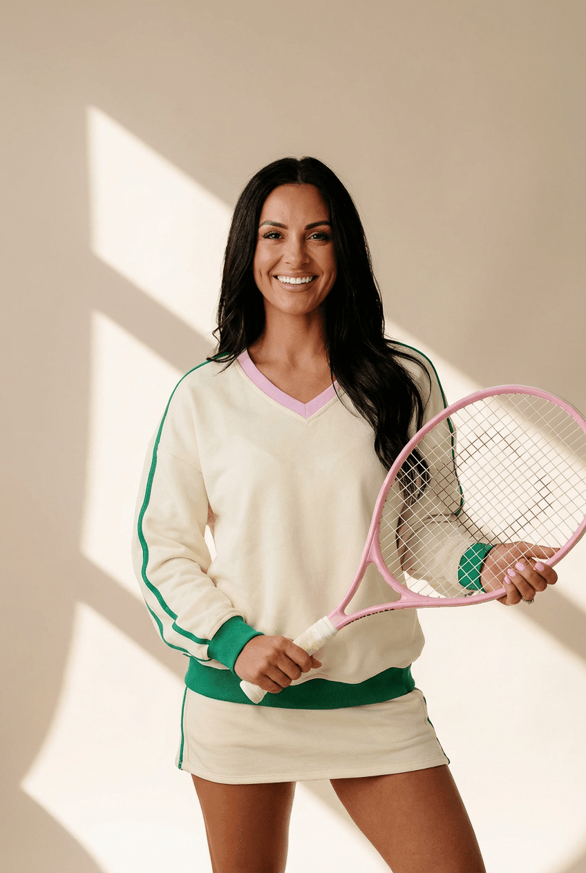 Woman holding a pink tennis racket against a neutral background