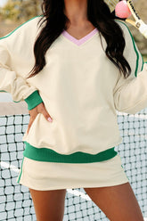 Person wearing a beige and green outfit with a tennis racket in the background