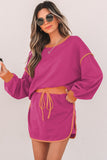 Woman wearing a magenta dress with a belt against a white background