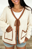 Woman in apricot knit cardigan with chestnut trim, tie front and patch pockets, front view