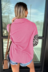 Woman in pink and white striped shirt with leopard print sleeves standing in front of glass door.