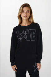Woman wearing a black sweater with 'LOVE' and star design on a white background