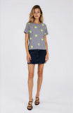 Woman wearing a gray t-shirt with yellow stars and a black skirt on a white background