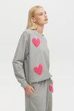 Woman wearing a gray sweatshirt with pink hearts on a white background
