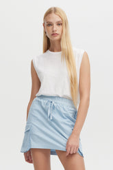 Woman wearing a white sleeveless top and light blue skirt on a white background