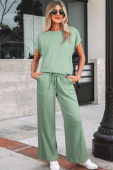 Woman wearing a green outfit standing on a sidewalk.