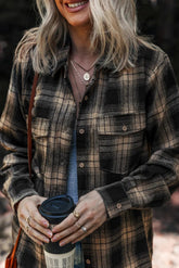 Person wearing a plaid shirt holding a coffee cup outdoors
