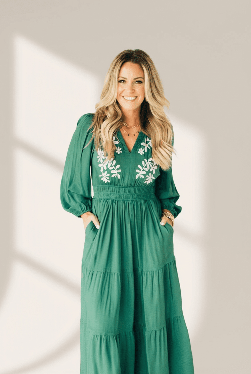 Woman wearing a green jumpsuit with floral embroidery against a neutral background