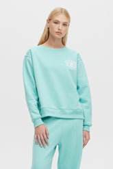 Woman wearing a light blue sweatshirt with a logo on a white background
