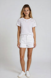 Woman wearing a white top and shorts with a plain background