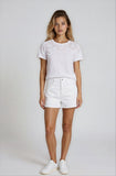 Woman wearing a white top and shorts with a plain background