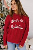 Woman in red cable-knit “fololo fololo” sweater with light blue jeans by Christmas tree.