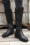 Black knee-high boots worn by a person standing on a wooden floor with a rustic background.