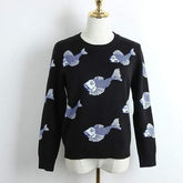 Black sweater with blue fish pattern on a mannequin against a white background