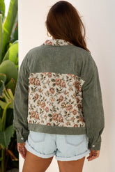 Person wearing a green jacket with floral back panel against a white background