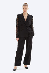 Woman wearing a black suit with lace sleeves on a white background