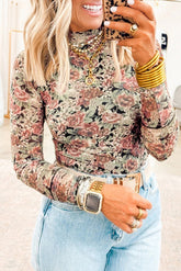 Woman wearing a floral long-sleeve top and jeans, holding a phone.