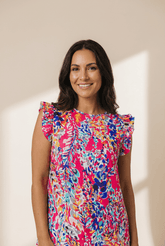 Woman wearing a colorful floral dress against a beige wall