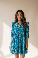 Woman wearing a blue floral dress against a beige background
